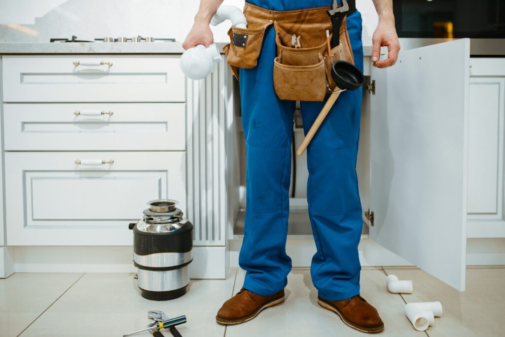 Male plumber installing water filter in kitchen